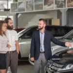 Kunden wählen gemeinsam mit einem Verkäufer in einem Autohaus ein Auto aus, um es zu kaufen